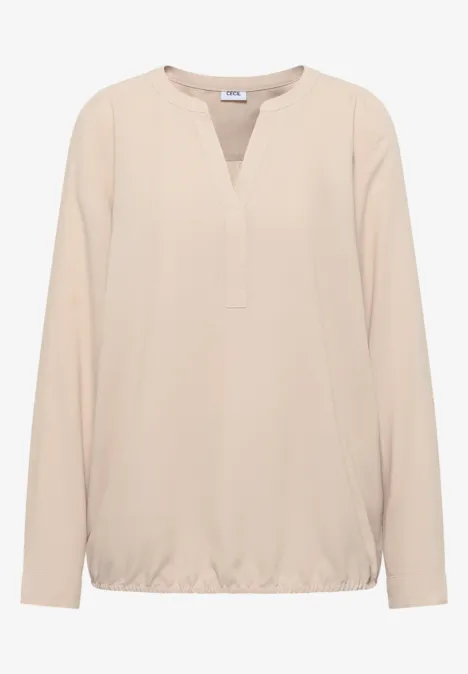 Beigefarbene Bluse mit V-Ausschnitt und langen Ärmeln.